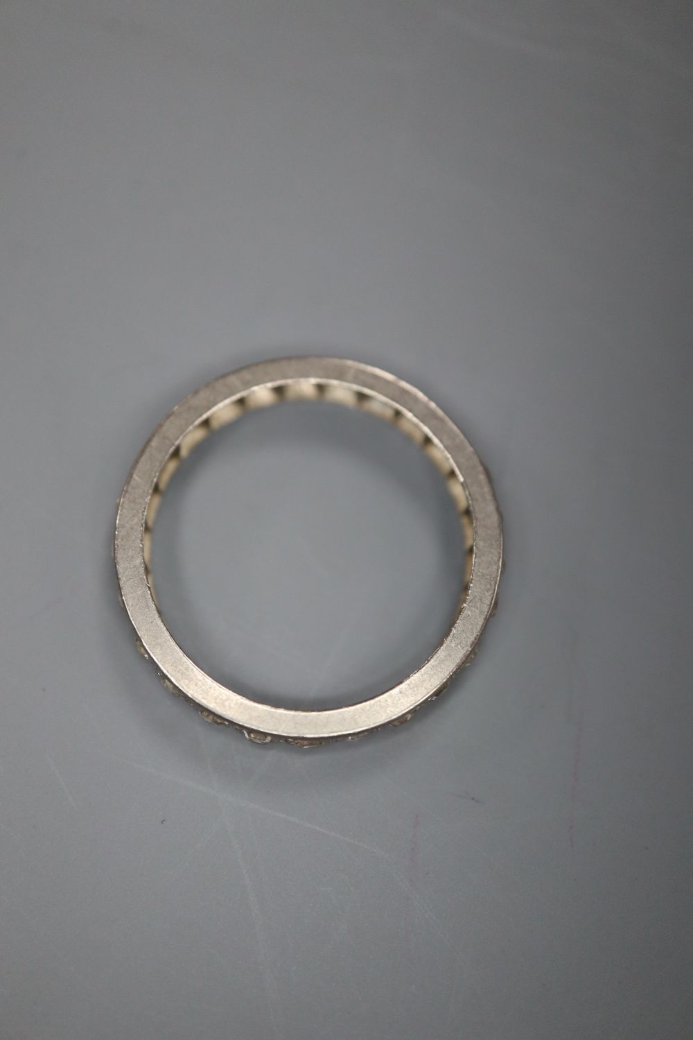 A white metal and diamond set full eternity ring, size N/O, gross 2.8 grams.